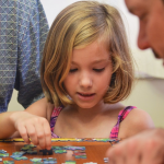 a girl making a jigsaw puzzle on a wooden table